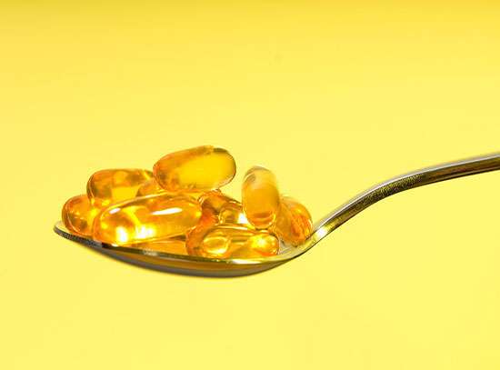 Picture of a spoon laden with omega-3 softgels.