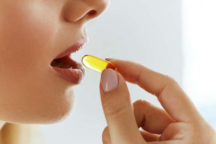 Female consumer taking omega-3 softgel dietary supplement